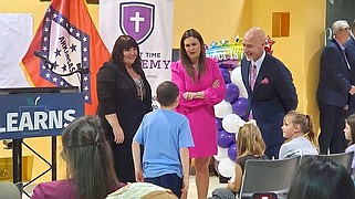 Twyla Lambe (from left), principal of Harvest Time Academy, Gov. Sarah Huckabee Sanders and Jacob Oliva, secretary for the Arkansas Department of Education, speak April 1 with a student following Sanders' announcement that the LEARNS Act Education Freedom Accounts will expand to include more students in the upcoming school year. (NWA Democrat-Gazette/Monica Brich)